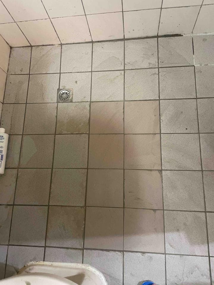 1) 照片顯示一個浴室地板,地板是由瓷磚構成的,瓷磚上有污垢