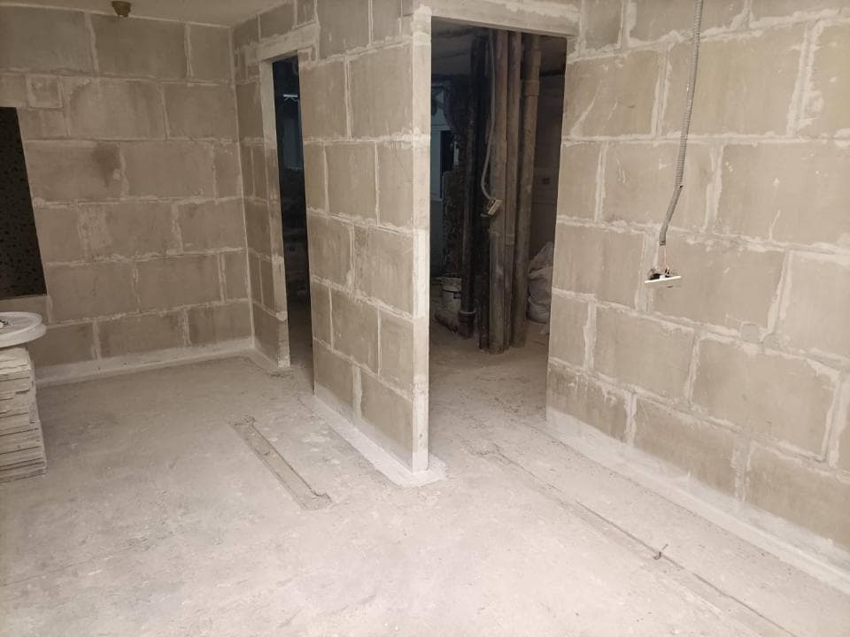 1) 照片顯示一間未完成的浴室,牆壁上裝有白色瓷磚,地板上鋪著水泥