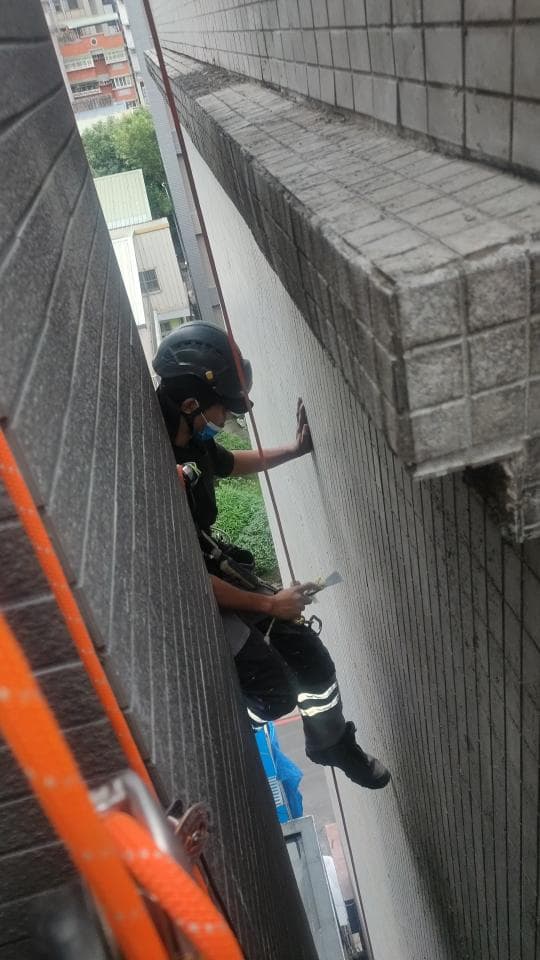 1. 照片中是一位身穿安全裝備的工人,正在建築物外牆上作業