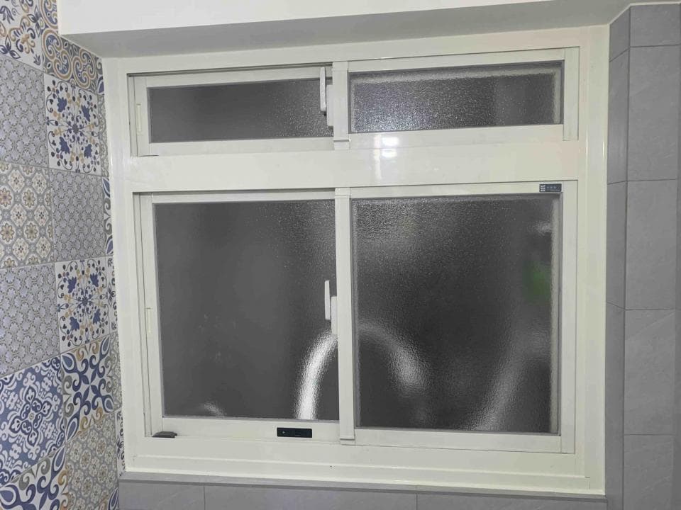 1) 照片顯示一個浴室的窗戶, 窗戶是白色鋁框的, 窗戶上有兩扇窗, 上面兩扇是固定窗, 下面兩扇是滑動窗, 窗戶上有一層毛玻璃