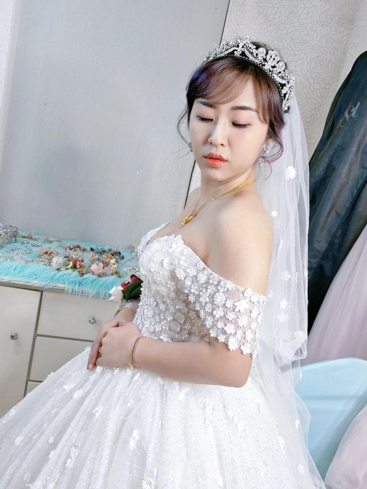 這張「婚紗照」的照片是一個穿著白色婚紗的新娘,她頭戴著皇冠,手拿著捧花,看起來非常美麗。