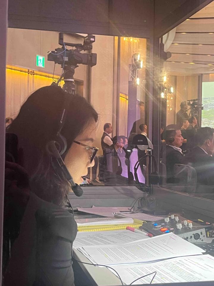 這張「錄音室」的照片是,一位女性坐在桌子前,她戴著耳機,面前放著文件,正在工作。