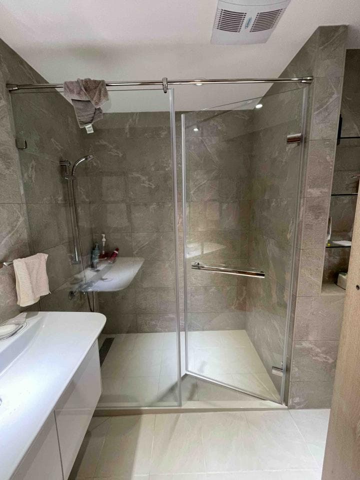 這張照片是一個現代化的浴室,浴室最顯眼的部分是安裝在牆上的玻璃淋浴門。淋浴門采用透明玻璃,並配有光亮的銀色框架,顯得格外簡潔時尚。