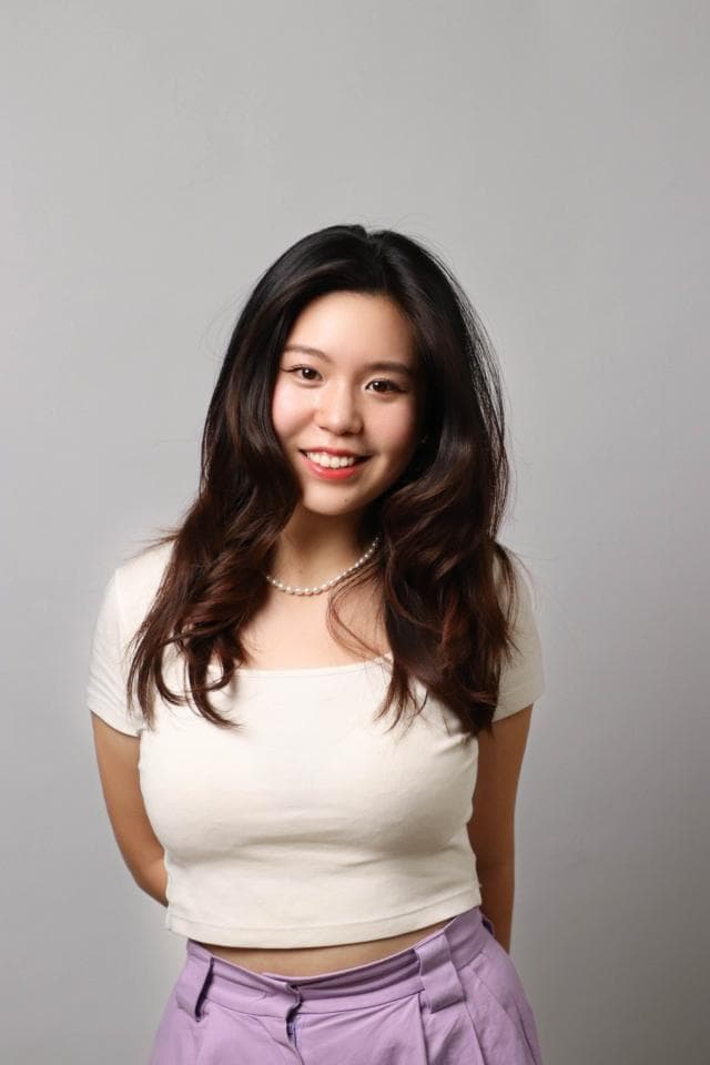 這張「一位年輕女性站在白色背景前,穿著白色短袖上衣和紫色長褲,面帶微笑」的照片是。