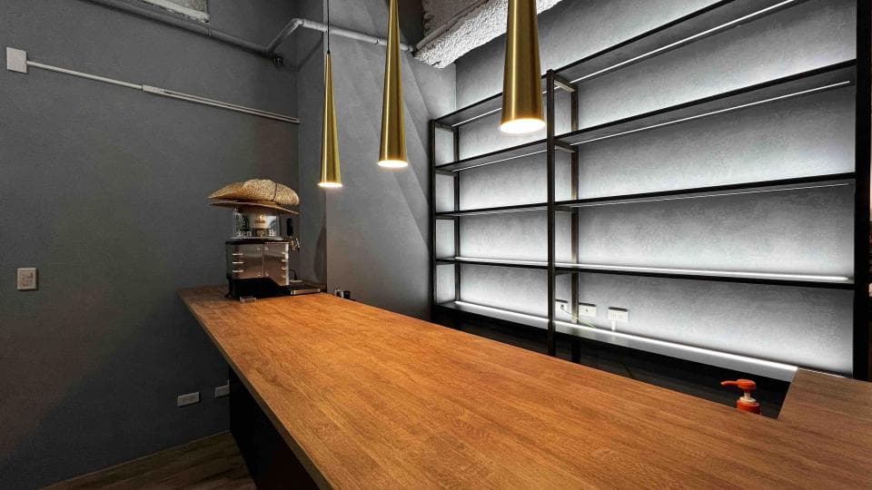 1) 照片顯示一個時尚的咖啡館或酒吧的內部,有一個木製的吧台和黑色的金屬架子,架子上裝飾著燈光