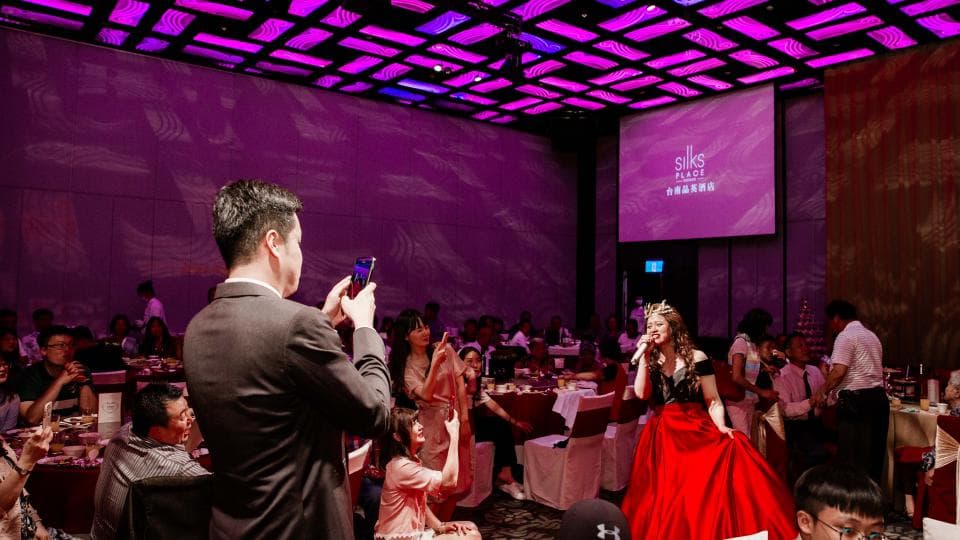 這張「婚禮」的照片是一對新人正在臺上唱歌,旁邊有許多賓客在觀禮。