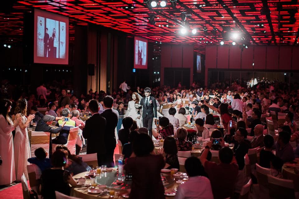 這張「婚禮」的照片是一對新人正在臺上,賓客們坐在桌子旁,舉行婚禮的宴會。