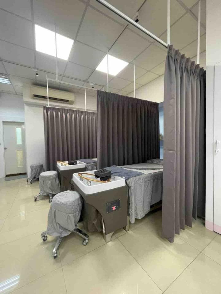 1) 照片顯示一個房間,房間裡有兩個按摩床,每個床都有自己的簾子,房間裡的牆壁是白色,地板是淺色的瓷磚