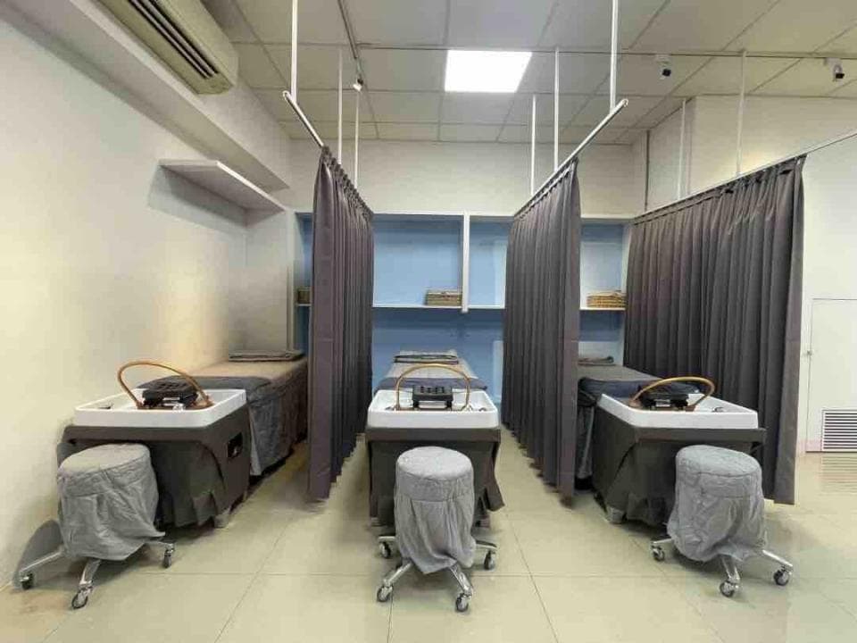 這張照片顯示一個室內空間,有三個治療床,每個床都配有床頭櫃和一個灰色的布製遮蔽簾