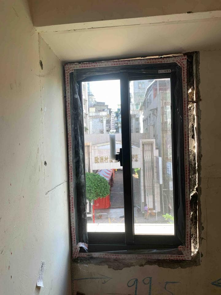 1) 照片顯示一扇裝在牆上的窗戶,窗戶是黑色的,窗戶上貼著紅色的膠帶