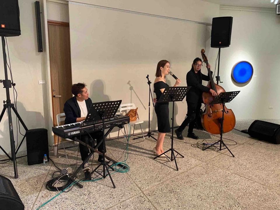 這張「室內音樂表演」的照片是,一個女人正在彈奏鍵盤,另一個女人正在唱歌,還有一個人在演奏大提琴。