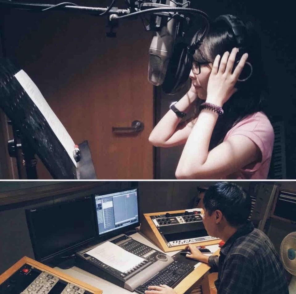 這張照片是一個錄音室,一位女生正在錄音,她戴著耳機,面前的麥克風很明顯。