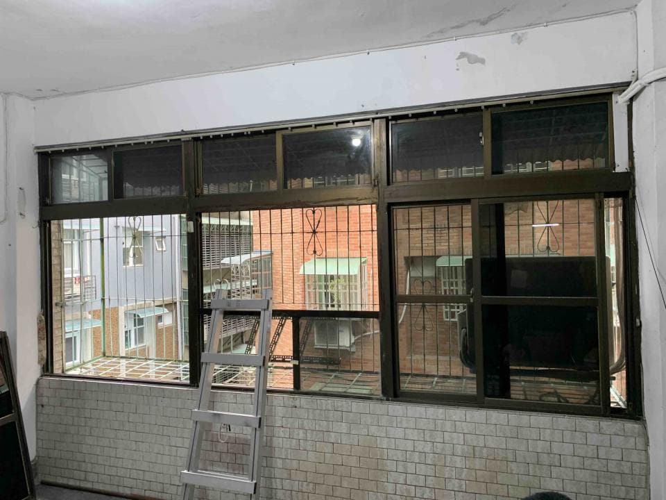 1) 照片顯示一個房間裡的一扇大窗戶,窗戶上有許多格柵,窗外可以看到幾棟建築物