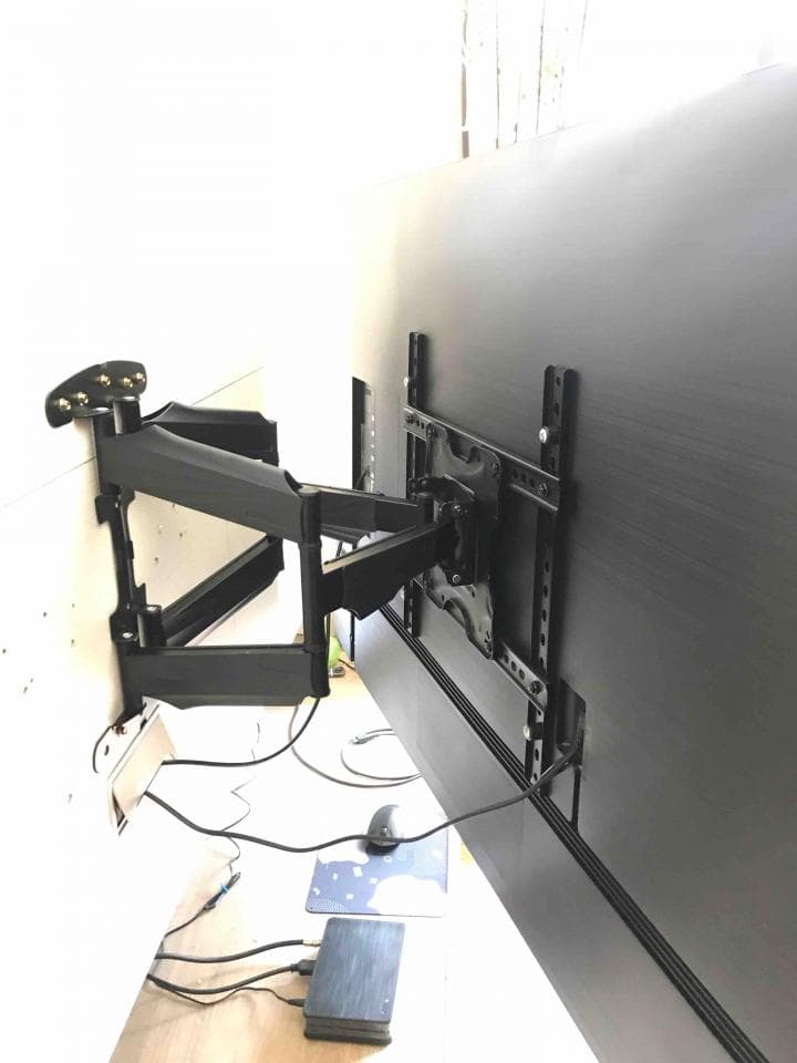 這張照片是一個電視牆壁架,電視牆壁架上有一個黑色的電視,電視牆壁架是黑色的金屬製成,可以旋轉和傾斜,並且安裝在牆上。