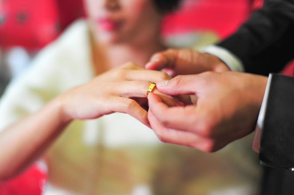 這張照片是一對新人交換戒指的畫面,畫面中,新郎正為新娘戴上金色的結婚戒指。