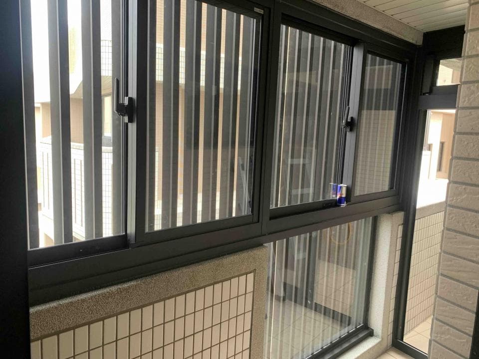 1. 照片顯示一間房子的陽台,陽台上有兩扇窗戶,窗戶是黑色的窗框,窗戶上裝有百葉窗