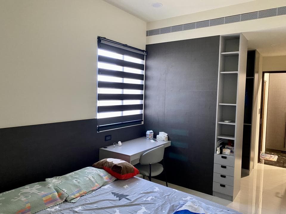 這張照片是一間現代化臥室,最重要的是一張舒適的雙人床,床頭板是深色的木頭,床單是灰色和白色的,床頭櫃上有台燈和一些裝飾品。