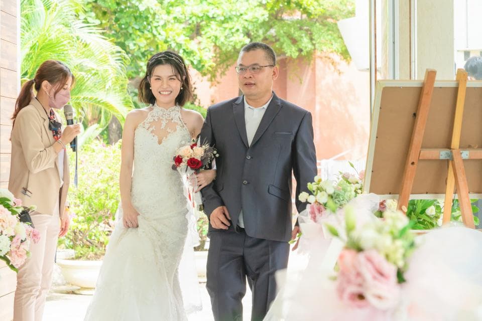 這張「婚禮」的照片是一對新人正在步入禮堂,新郎穿著深色西裝,新娘穿著白色婚紗,他們手牽手,露出幸福的笑容。