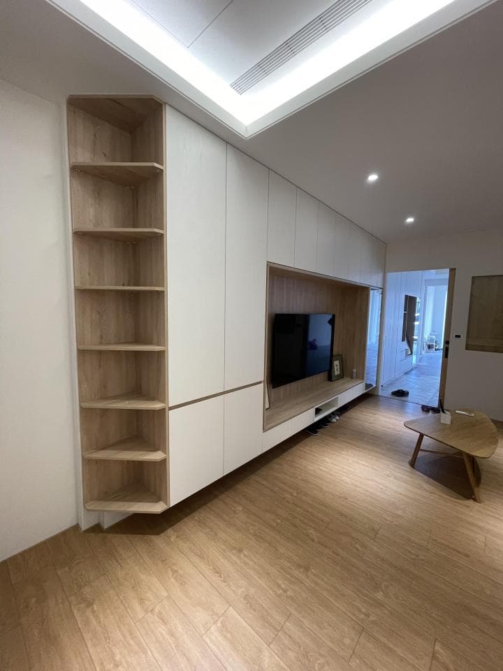 這張照片是一個現代化的客廳,其中最顯眼的部分是牆上設計的嵌入式電視櫃,它結合了開放式層架和封閉式櫃體,提供充足的儲物空間,同時也為電視機提供了完美的展示位置。