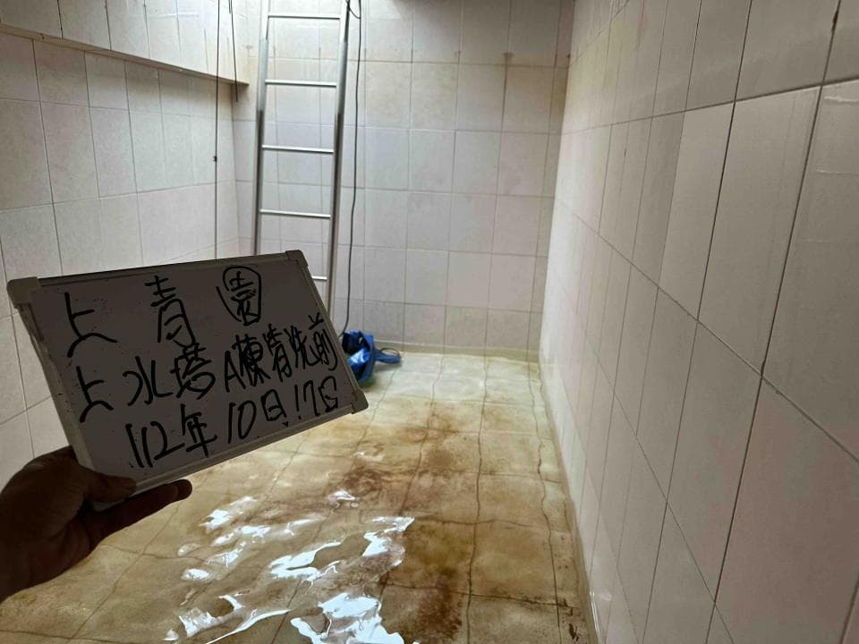 這張照片是一張寫著「七月上北陵A棟樓梯間 112年10月1日」的白板,白板放在一個潮濕的房間裡,房間裡有一把梯子。