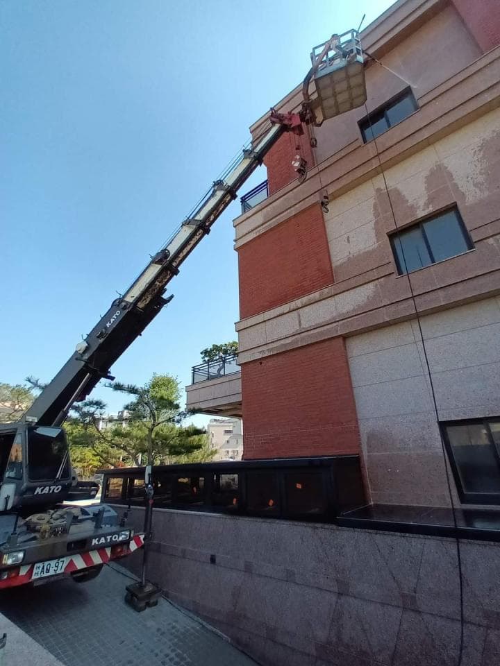 1) 照片顯示一台卡車起重機,正在建築物旁,將一台吊籃升至高處