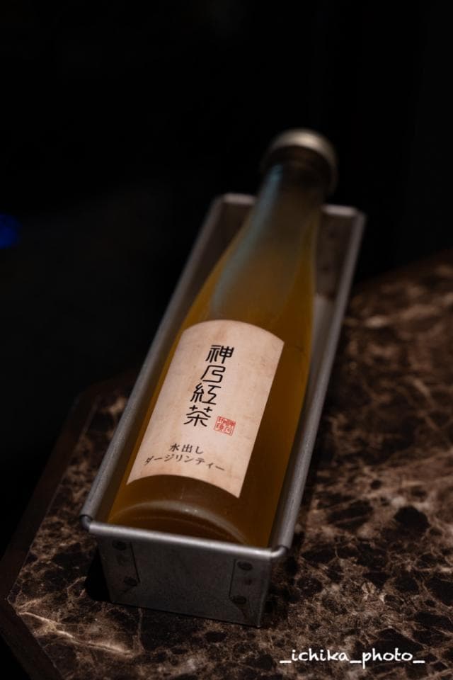 這張「酒瓶」的照片是一瓶裝在金屬盒裡的黃色飲料,酒瓶上有日文和中文的標籤。