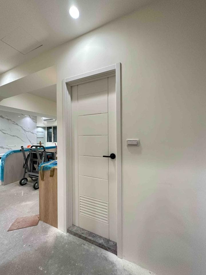 這張照片是一扇白色木門,門上有黑色的門把,门下有灰色石板。