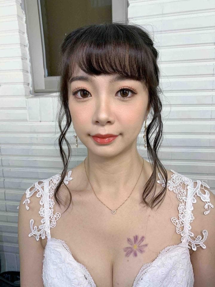 這張照片是一個穿著婚紗的女性,她看起來很漂亮,頭髮做了一個精緻的造型,並且有一個精緻的項鍊。