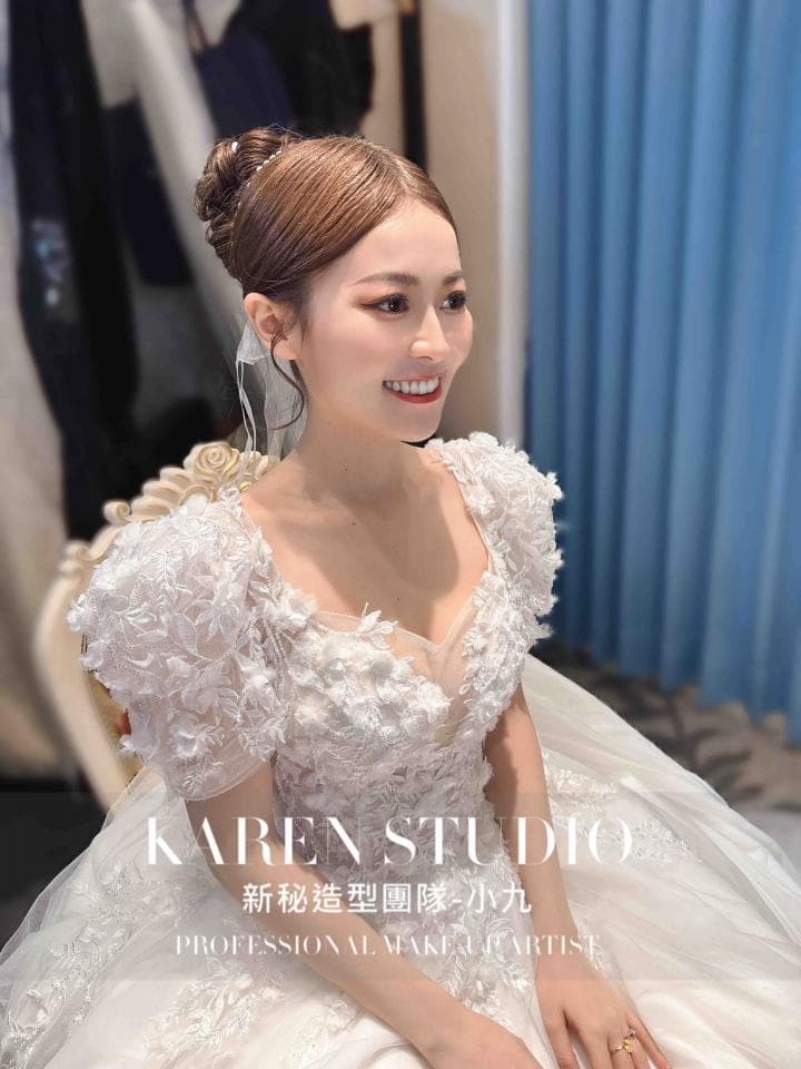 這張「婚紗照」的照片是一個穿著白色蕾絲婚紗的新娘,她的頭髮盤成一個優雅的髮髻,並帶有精緻的頭飾。她正在微笑,顯得十分幸福。