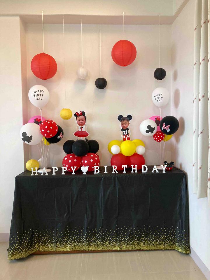 這張照片是一個米奇主題的生日派對佈置,最重要的是黑色的桌巾上有著金色亮片和白色字體寫著“Happy Birthday”,營造出歡樂的氣氛。