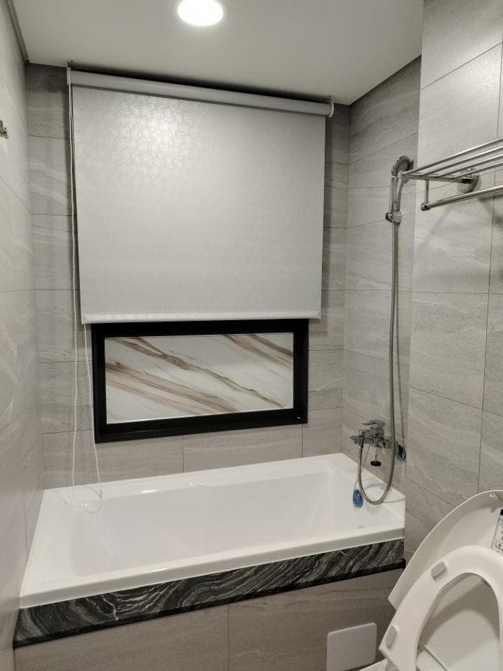 1) 照片顯示一間浴室,浴室裡有浴缸、馬桶、窗戶和淋浴設備