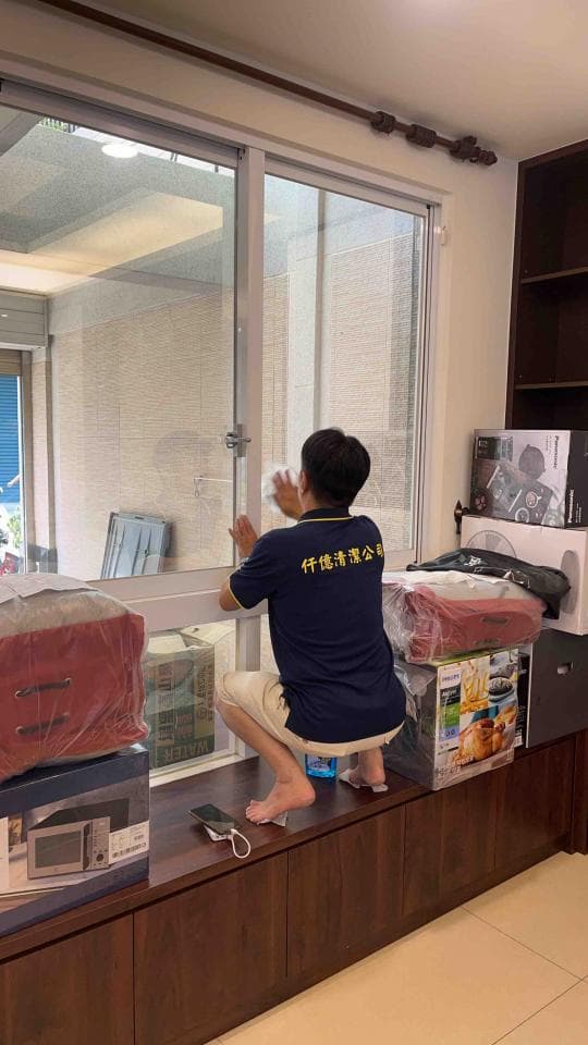 1) 照片顯示一個男人坐在窗戶旁的窗台上,他正在清理窗戶