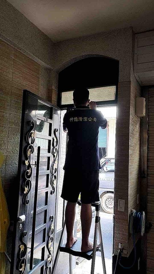 1) 照片顯示一名身穿黑色上衣和短褲的男性站在梯子上,正在安裝門窗