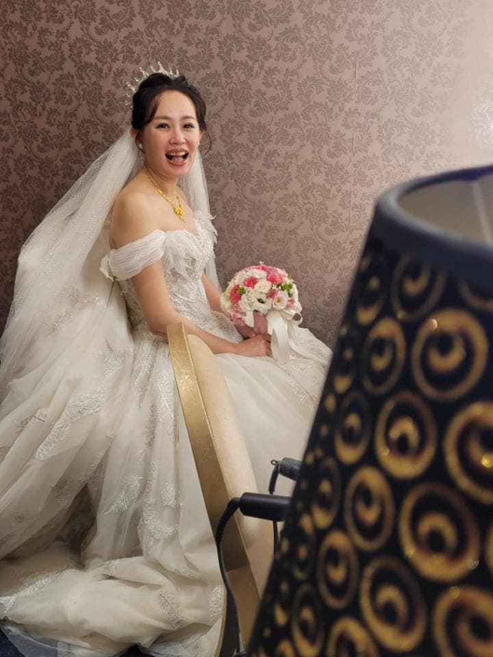 這張「婚禮」的照片是一個穿著婚紗的新娘,她坐在椅子上,拿著一束花,露出開心的笑容。