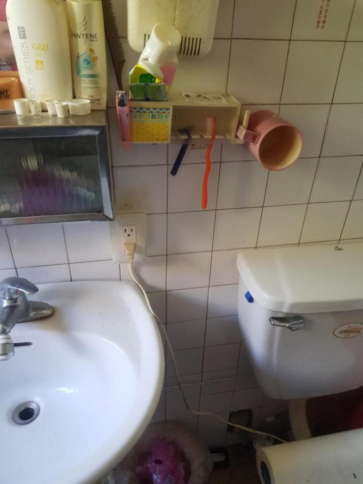 這張照片是浴室洗手台和馬桶。洗手台是白色的,上面有一個水龍頭,旁邊還有一個插座。馬桶也是白色的,旁邊放著一個紙巾盒。