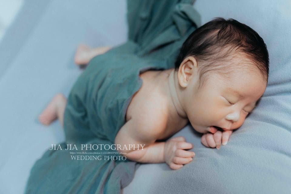 這張「嬰兒」的照片是一個可愛的嬰兒在睡覺,他被綠色的毯子包住,睡得很香。