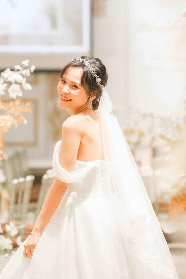 這張「婚禮」的照片是一個穿著白色婚紗的新娘,她微笑著轉過身,頭上戴著一個閃閃發光的頭飾。