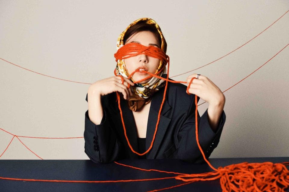 這張照片是一名女子被紅線蒙住眼睛,她似乎正試圖解開紅線。