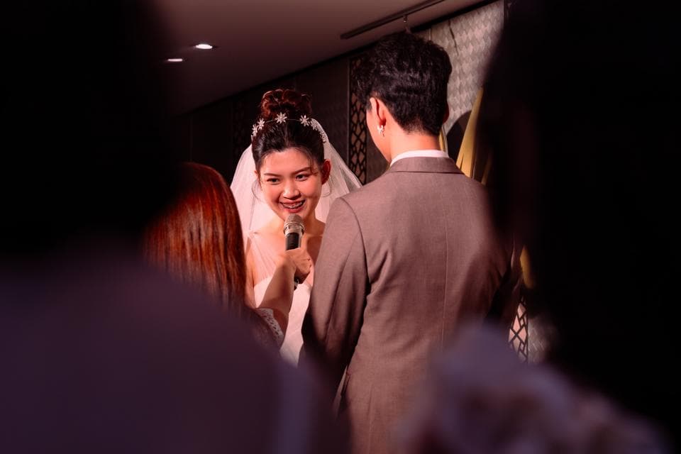 這張婚禮的照片是一對新人正在接受祝福,新娘穿著婚紗,新郎穿著西裝,他們正在看著鏡頭微笑。