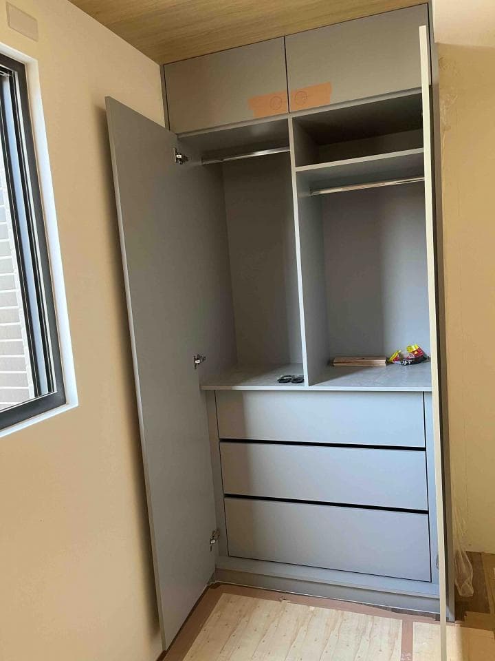 這張照片是一間臥室裡面的衣櫃。 衣櫃裡面有三個抽屜,衣櫃門是打開的,可以看到衣櫃的內部空間。