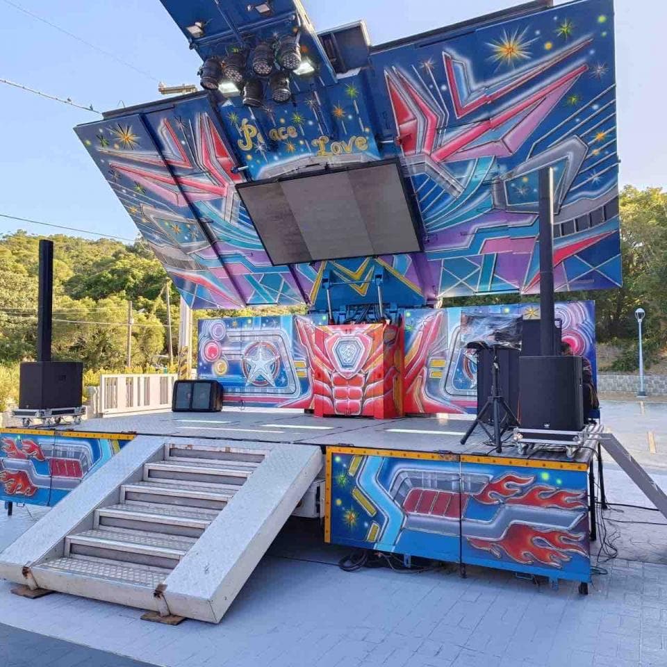 1) 這張照片顯示一個彩繪舞台,上面有大型揚聲器、燈光設備以及一個大螢幕