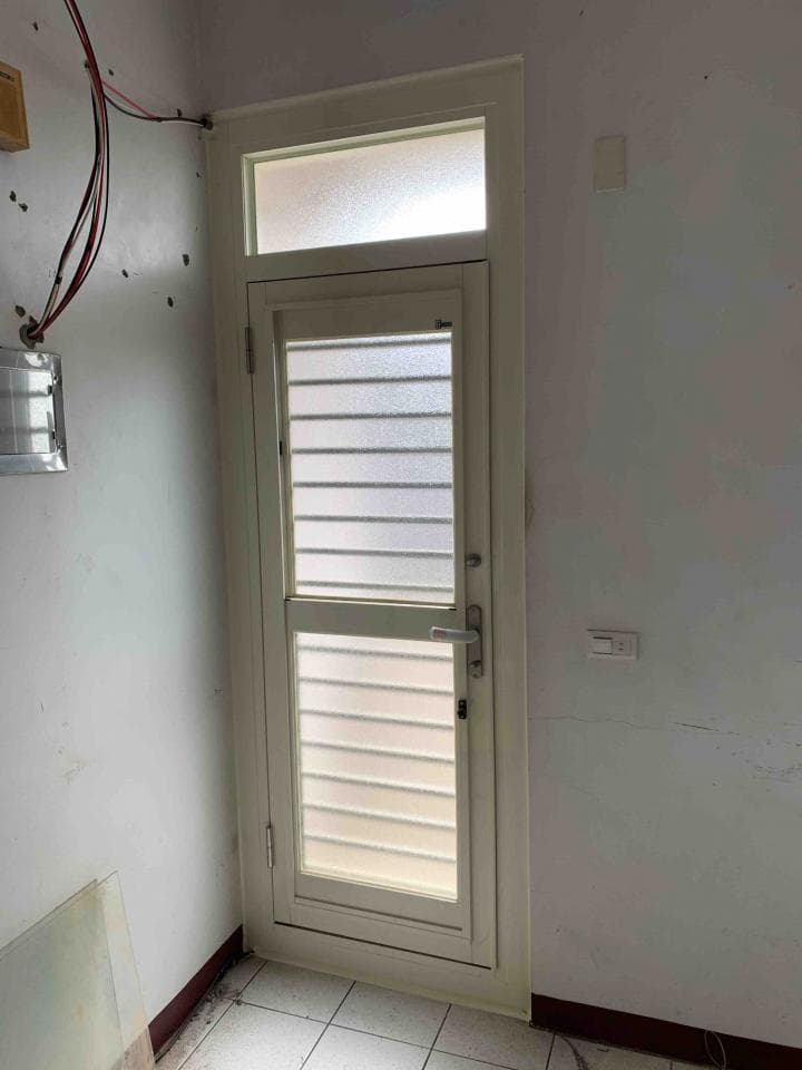 這張照片是一扇白色的門,門上有一個透明的玻璃窗和一個金屬把手。