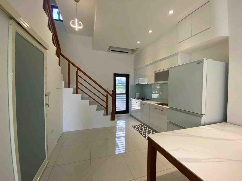 1) 照片顯示一間現代廚房,配有白色的櫥櫃、冰箱、流理台和淺色瓷磚地板