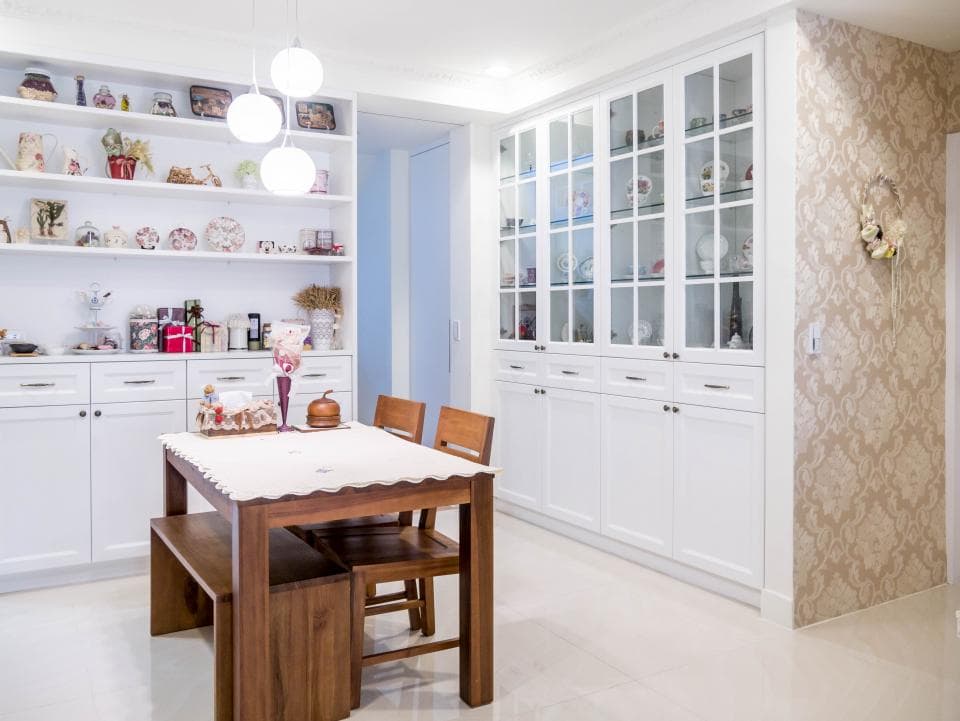 這張照片是一張現代化的廚房,最重要的是木製餐桌,桌上放著白色桌巾,餐桌旁有兩張木椅,牆上有一排白色櫃子,櫃子裡放著裝飾品。