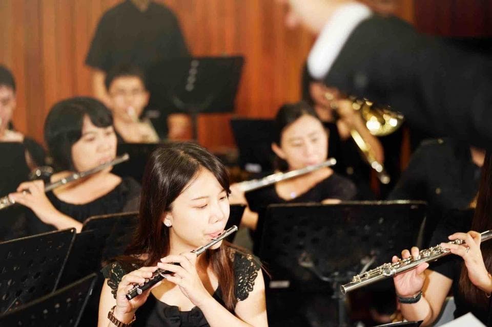 這張「樂團演奏」的照片是,一群人坐在椅子上,吹奏著長笛,他們身穿黑色衣服,神情專注。