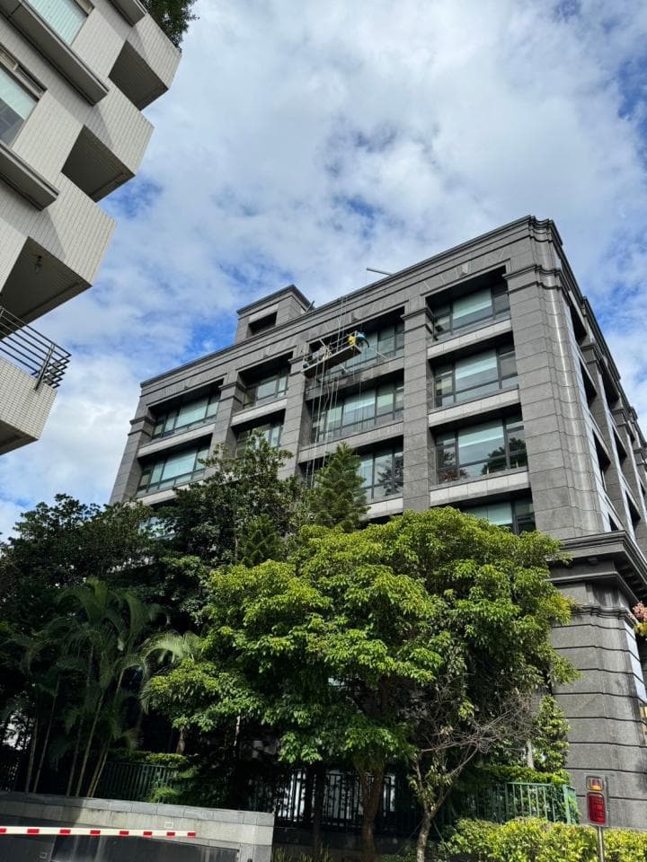 1) 照片顯示一棟灰色建築物,建築物外觀有許多窗戶,前方有綠色的樹木