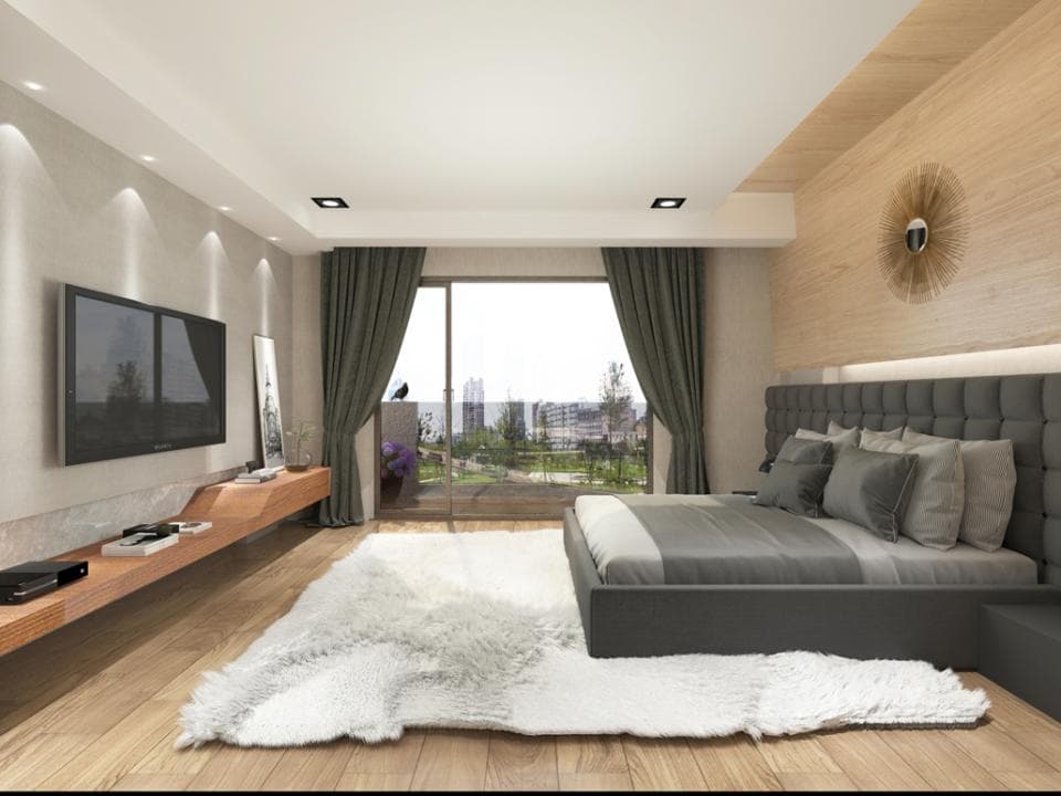 這張「臥室」的照片是一個現代化的臥室,房間裡有一張大床,床頭板是灰色的,床邊有一張小桌。床的旁邊有一張白色地毯,房間的牆壁上有一個電視。