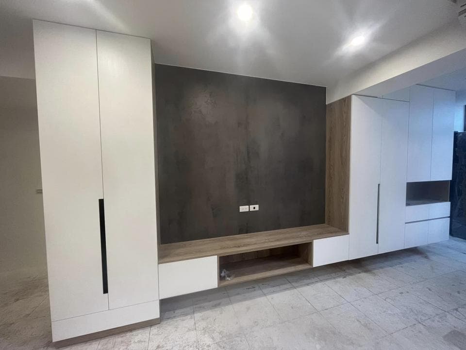 這張照片是一間現代化的客廳,牆上裝飾著灰色水泥牆面,看起來簡約又時尚,並搭配木紋的電視櫃,讓空間更顯溫馨。