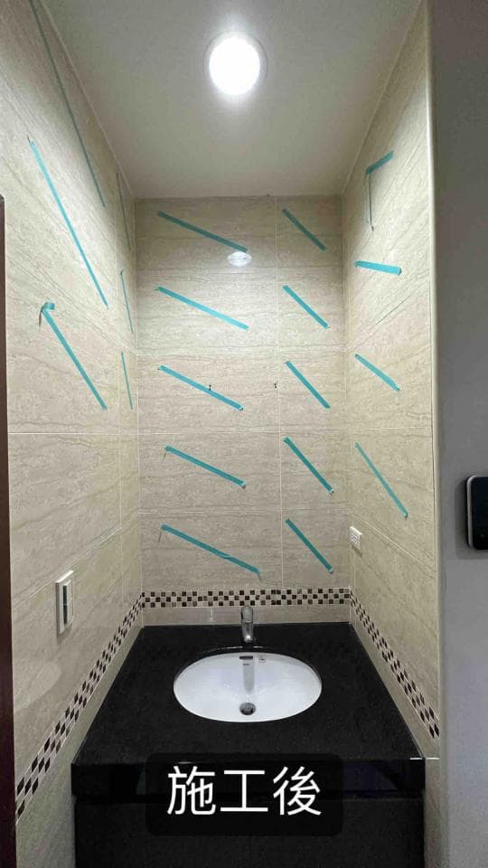 1) 照片顯示一個正在裝修的浴室,浴室裡有一個洗手台,牆上貼了許多藍色的膠帶,地板上還有一些黑色的小方塊