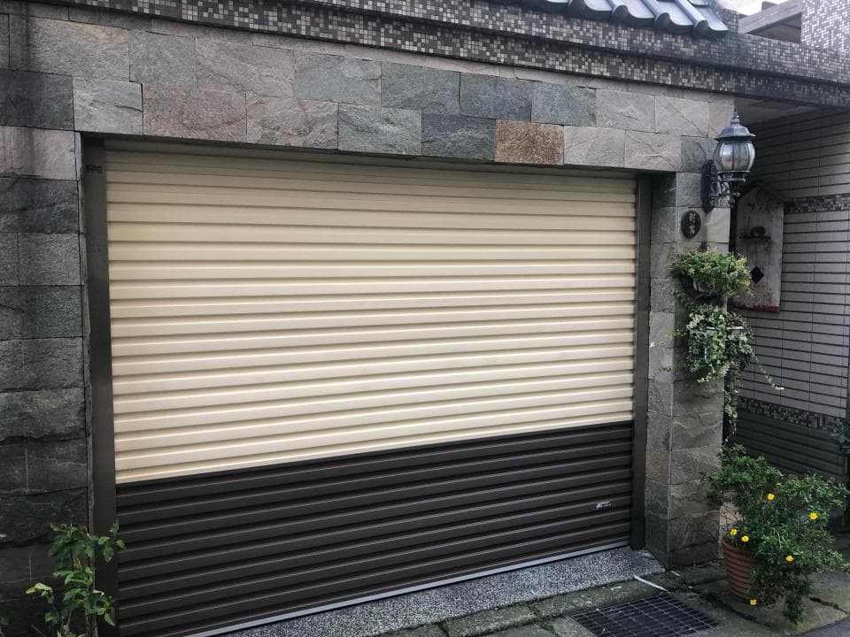 這張照片是一個帶有捲簾門的建築物。捲簾門是由淺色和深色兩部分組成,淺色部分在上面,深色部分在下面。